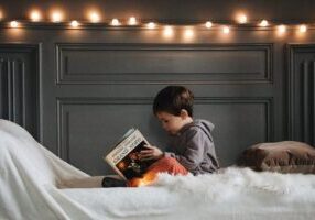 A kid reading a book in their soundproof bedroom
